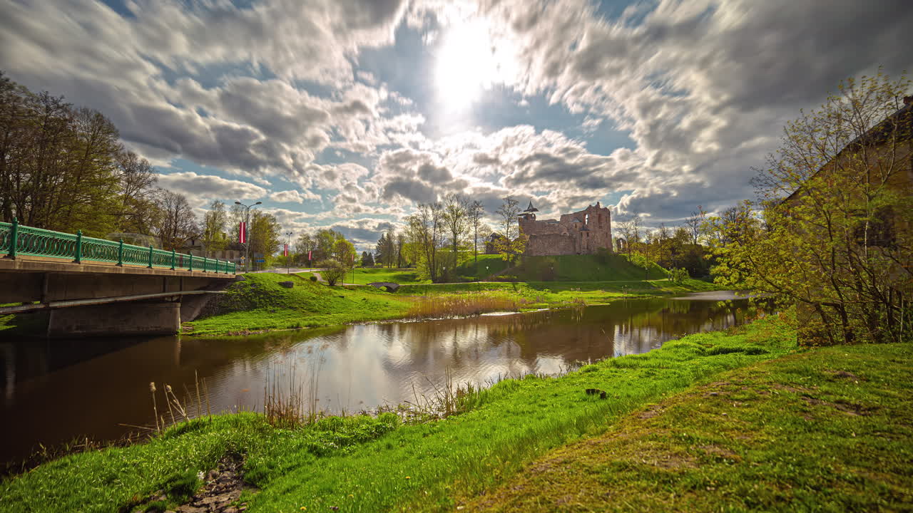 белые облака проплывают в голубом небе над рекой берзе и руинами замка добеле