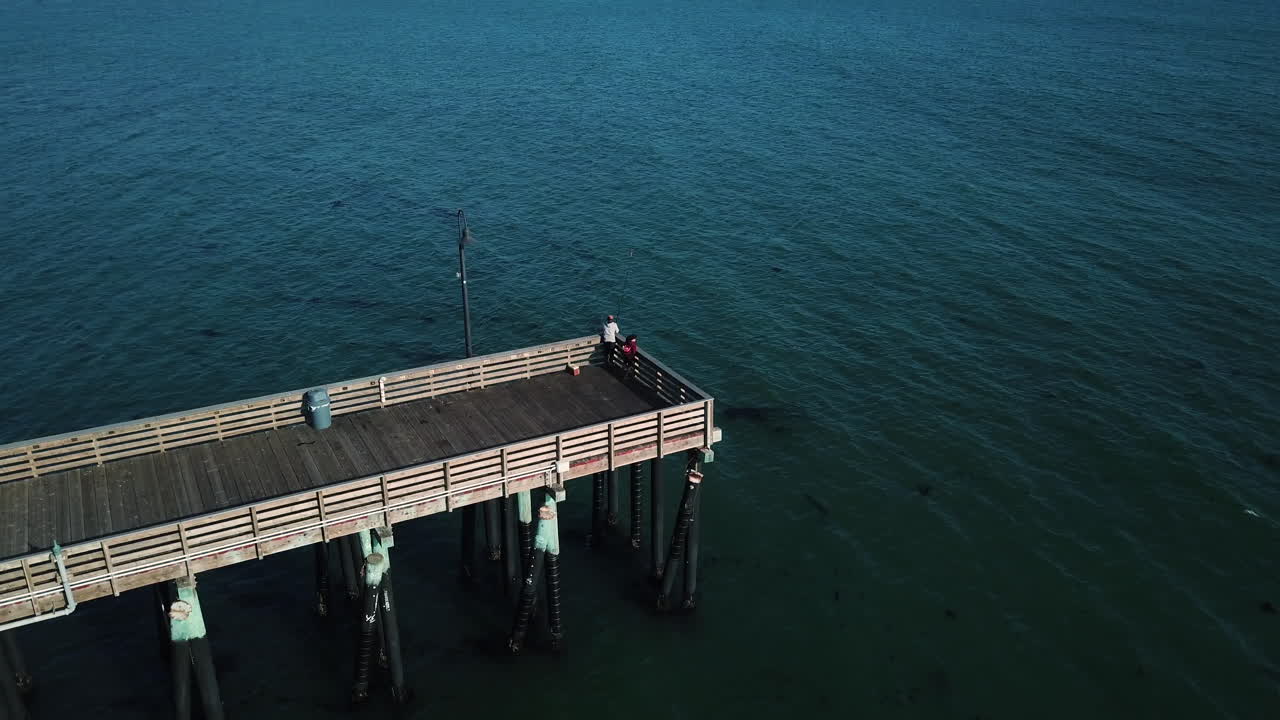 hombre pescando al final del muelle por la tarde