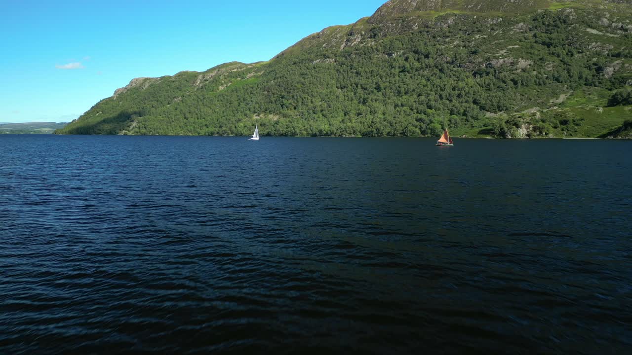 여름 날 어두운 호수 표면 위에서 숲이 우거진 언덕을 배경으로 작은 요트를 향해 빠르고 낮은 비행