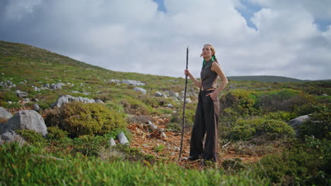 solo traveler trekking green hillside on summer day. adventure woman posing