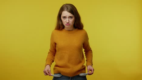 frustrated upset poor girl with brown hair in pullover turning out pockets gesturing no money