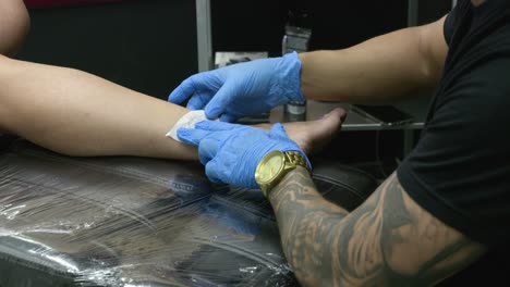 se coloca un pedazo de papel con el dibujo del tatuaje en la pierna del cliente