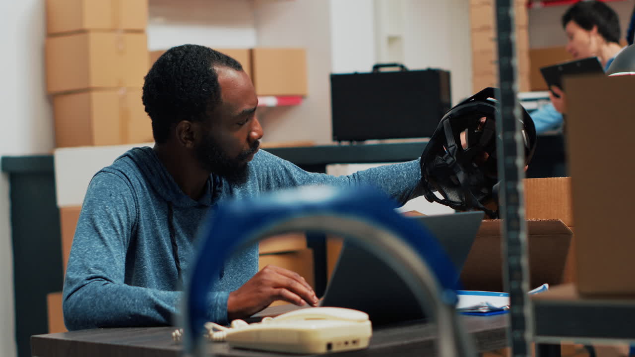 Man working on laptop in warehouse with boxes