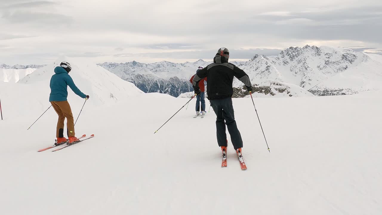 espectáculo cinematográfico de esquí con 3 atletas de esquí en una estación de esquí en lo alto de las montañas con impresionantes vistas panorámicas sobre las cimas de las montañas nevadas