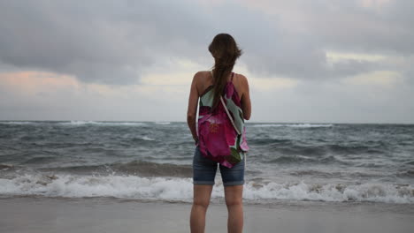 Cinematic-shot-at-sunrise-of-a-woman-admiring-the-beauty-of-the-ocean-and-having-bad-waves