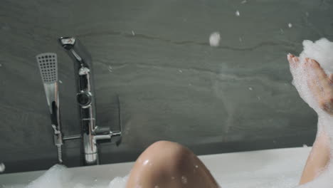 Attractive-woman-bathing-indoors.-Cute-girl-having-fun-with-foam-in-bathroom.
