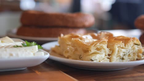 close-up of a delicious turkish pastry, with cheese filling, on a white plate, with bread in the background.