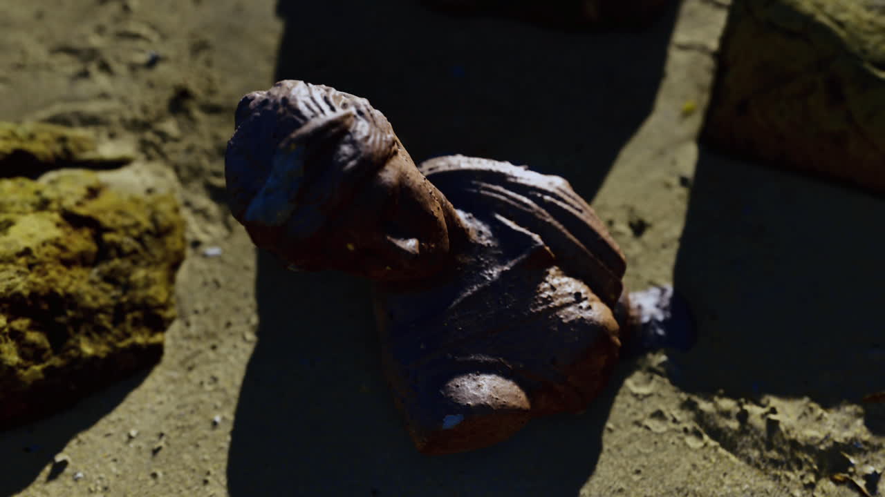 Ancient sculpture fragment discovered on the sandy shore at sunset