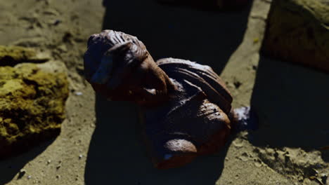 ancient sculpture fragment discovered on the sandy shore at sunset