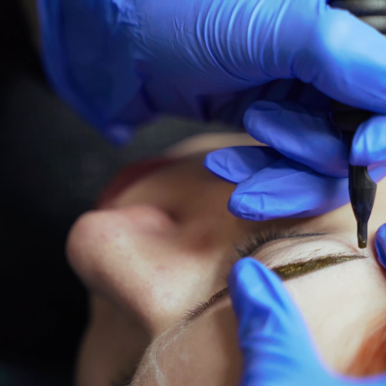 Procedure of eyebrow tattoo with using a needle for applying a dye in a beauty salon. Cosmetology. Beauty Industry