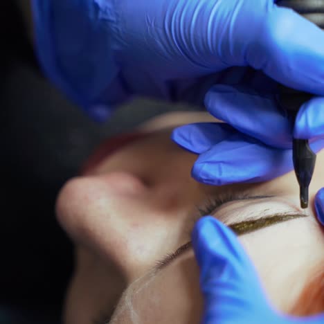 procedure of eyebrow tattoo with using a needle for applying a dye in a beauty salon. cosmetology. beauty industry
