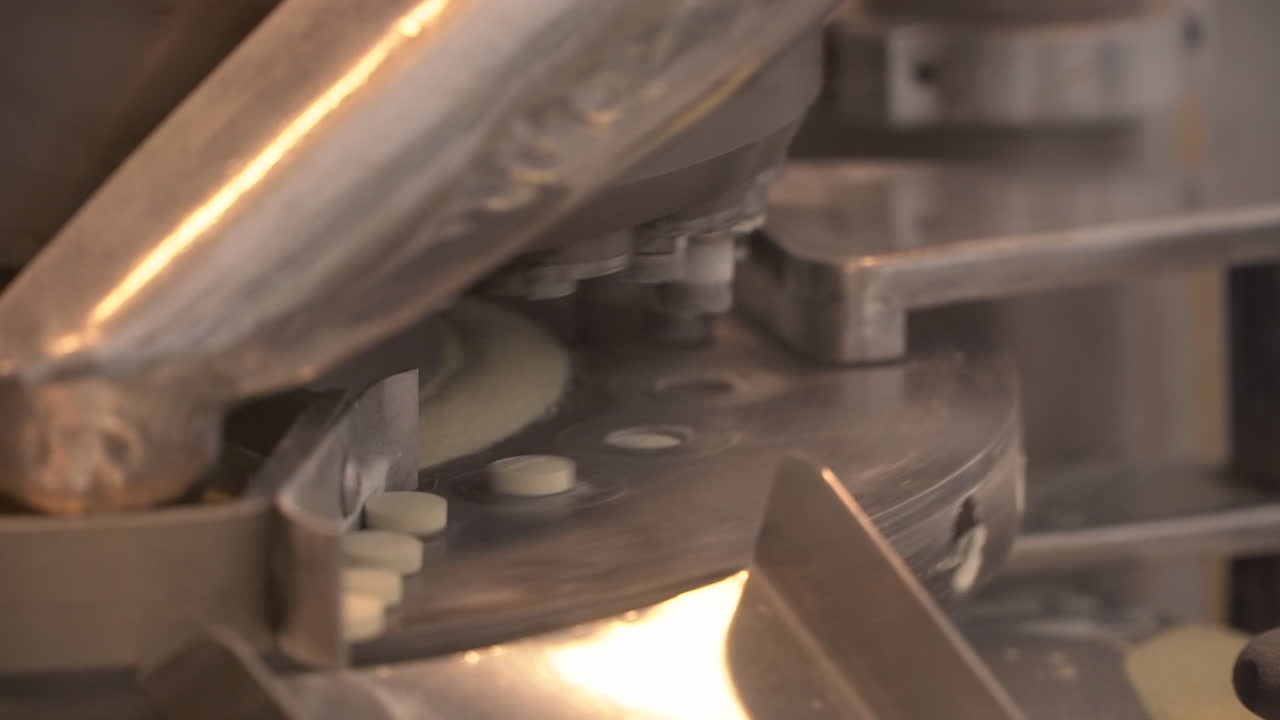 Pharma laboratory industrial machine circulates yellow drug pills, still close up