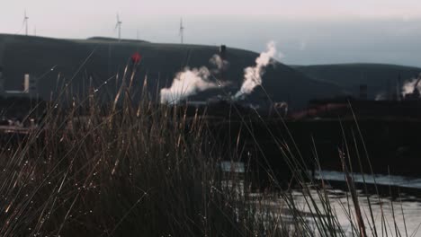 focus pull to industrial steelworks factory with wind turbines