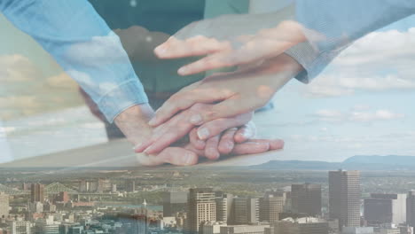 animation of business colleagues stacking hands, over cityscape