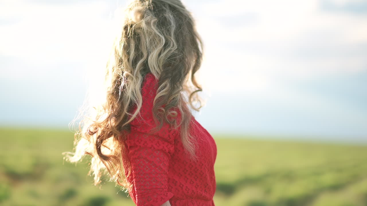 A young woman enjoys the sunlight as she smiles softly, surrounded by open skies and natural light