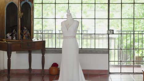 long white wedding dress displayed on mannequin in country house room