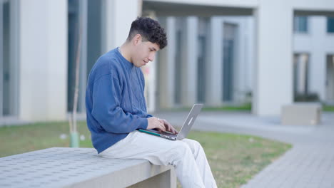 young student working on laptop outdoors in university campus