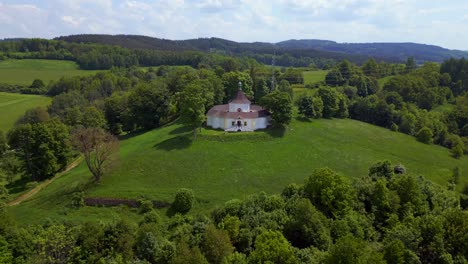Faith-in-God-Beautiful-aerial-top-view-flight-Round-Chapel-on-mountain-hill,-Krumlov-Czech-Republic-Summer-2023