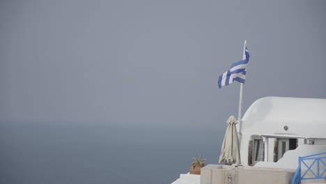 the greek flag blowing in the wind in oia on the island of santorini greece