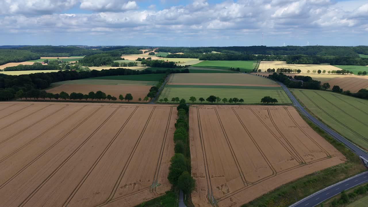 American farm fields countryside with car on intersection during cloudy day. Aerial lateral wide shot. Clouds at sky. Golden and green fields in USA. Panorama view. Cultivation and environment theme