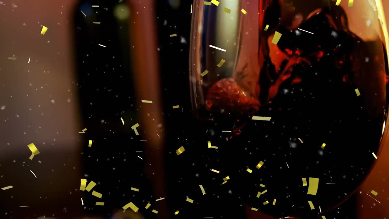Golden confetti falling against close up of wine pouring into a glass