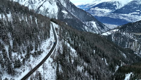 Truck-driving-down-over-the-long-black-asphalt-road-with-amazing-view-on-the-high-swiss-mountains