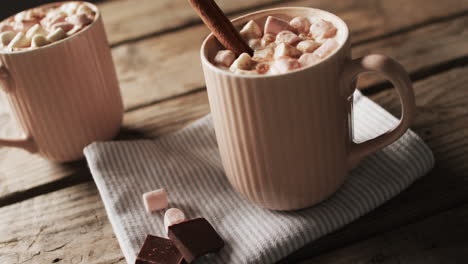 video of mugs of chocolate, marshmallows, christmas decorations and copy space on wooden background