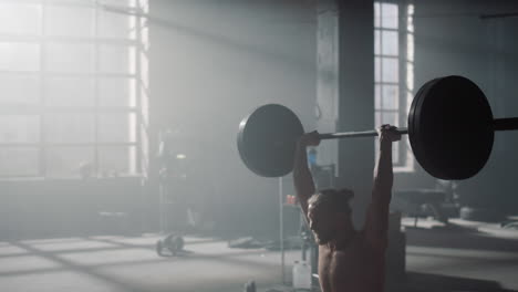 man doing overhead squat with barbell during. strong sportsman lifting weights