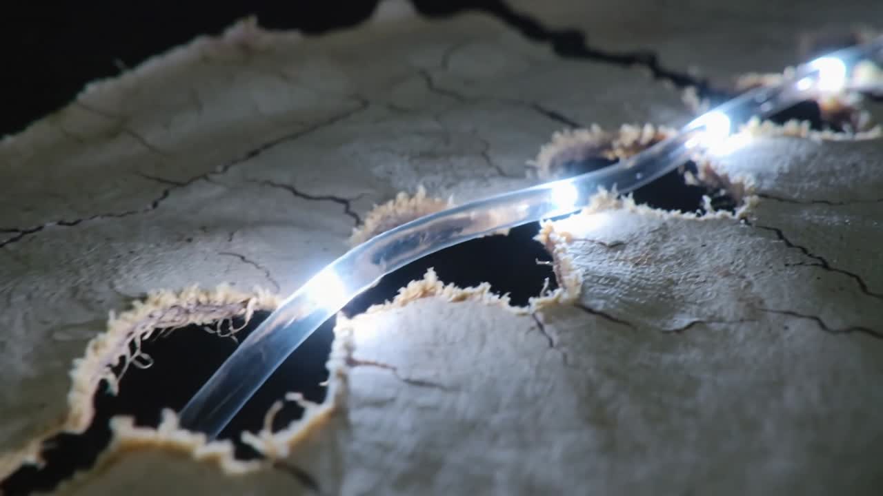 Sliding after tiny shift, clear LED tube moving diagonally over cracked fiber sheet lighting holes