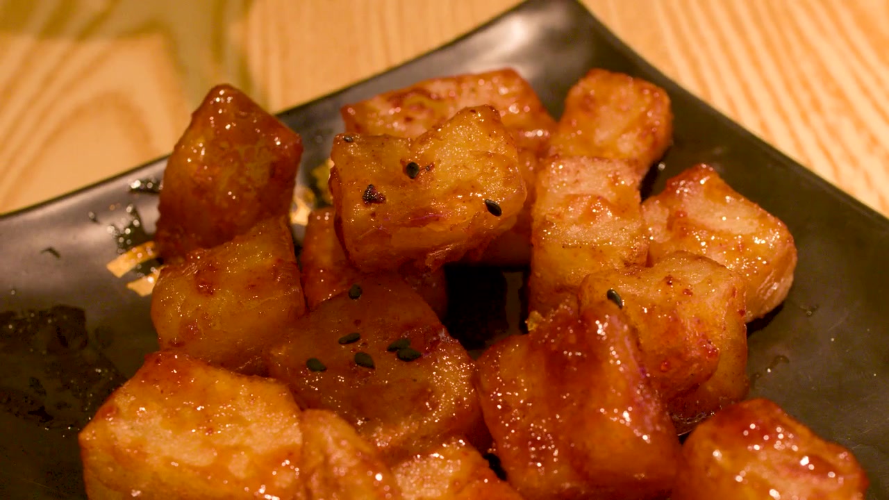 Mangiare cubetti di tofu fritto glassato con le bacchette