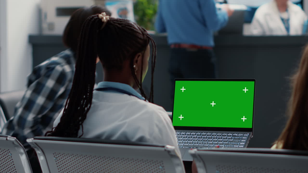 Medico che usa un laptop con schermo verde nella sala d'attesa dell'ospedale