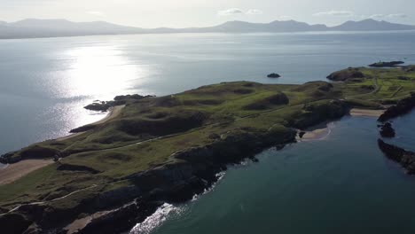 Aerial-view-across-Ynys-Llanddwyn-and-hazy-Snowdonia-mountain-range-with-shimmering-Irish-sea-at-sunrise