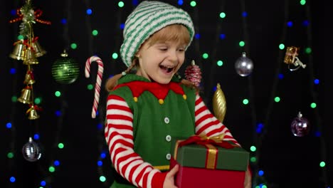 Kid-girl-in-Christmas-elf-Santa-helper-costume-getting,-receiving-present-gift-box.-New-Year-holiday