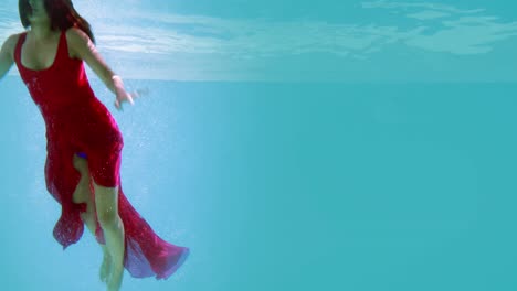 morena en vestido de noche buceando en la piscina