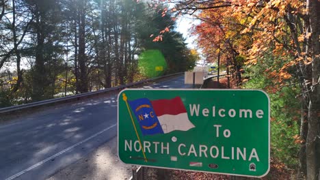 welcome to north carolina sign along winding road lined by colorful trees in autumn