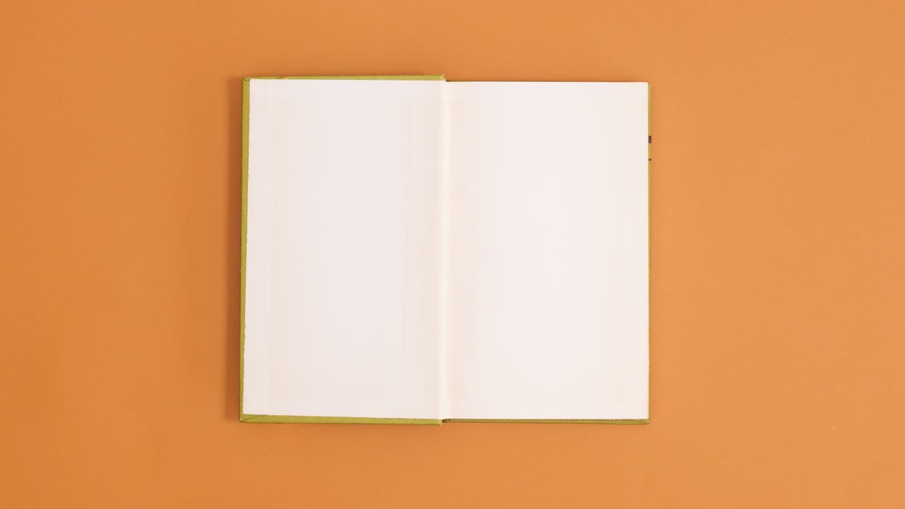 Green vintage hardcover book appear and open with copy space on orange background. Stop motion flat lay