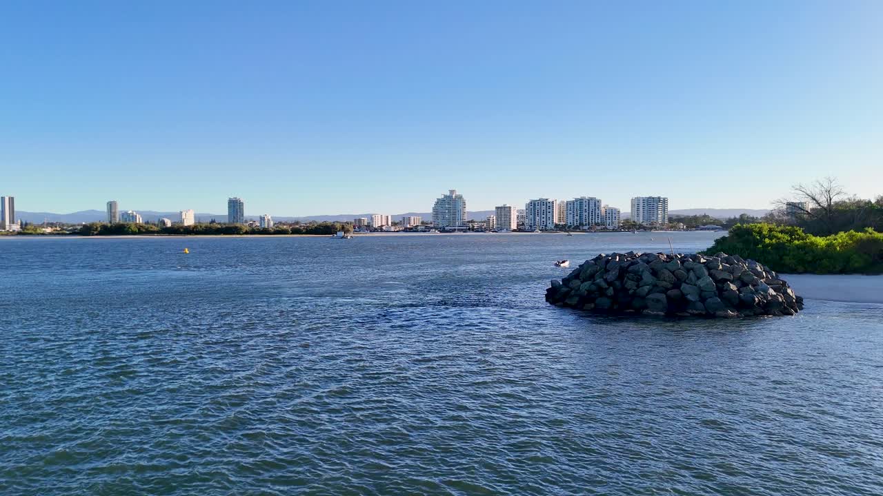 Drone captures serene waterway with buoy and rocky bluff under clear sky at Gold Coast, Australia