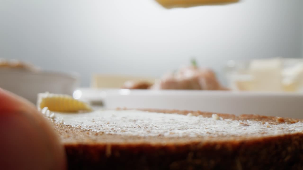 Young woman spreading nut butter onto toast in kitchen, closeup. High quality 4k footage