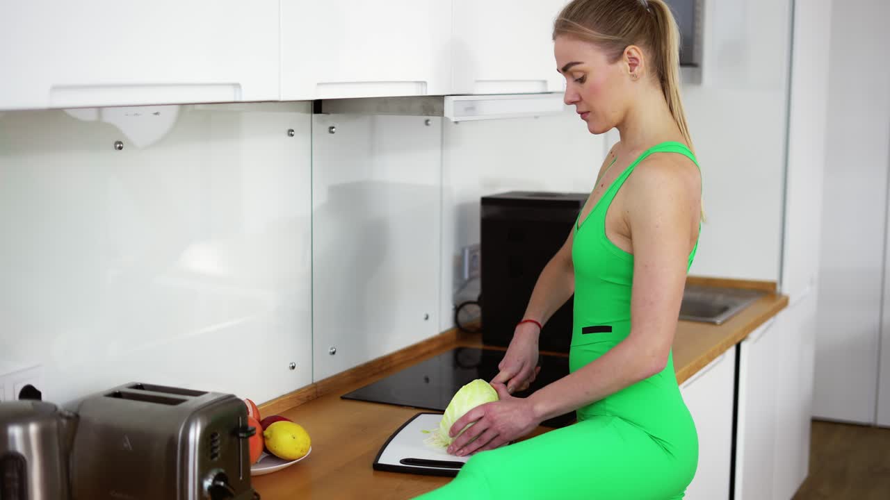 Donna flessibile che cucina in cucina in abbigliamento sportivo.