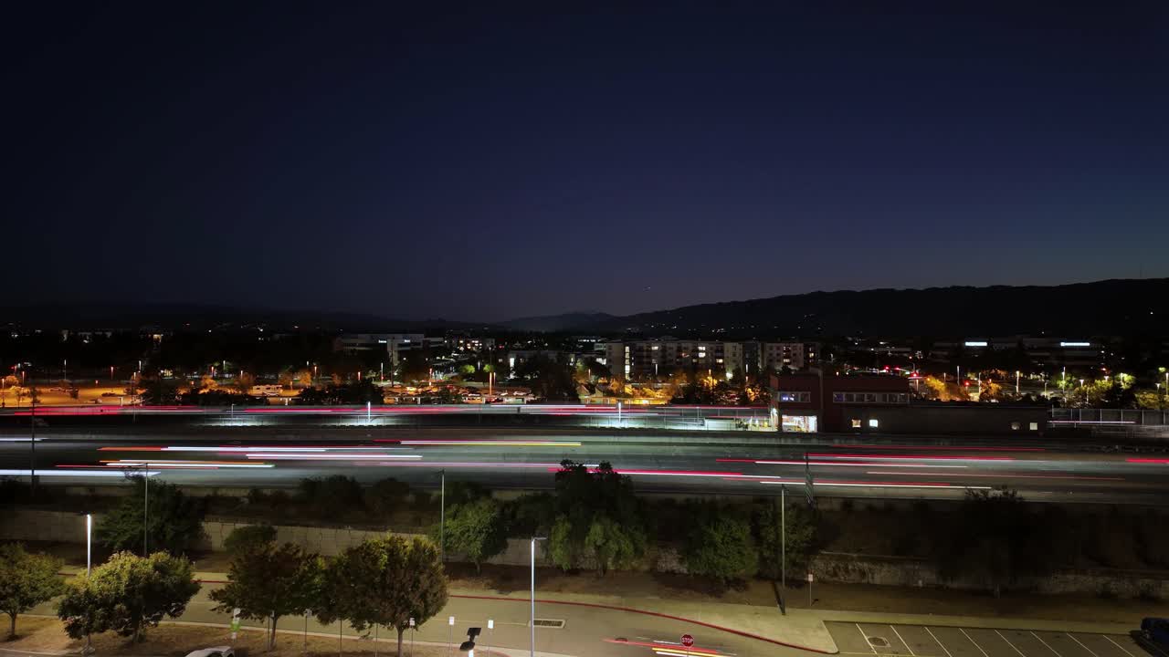 Evening falls over Dublin, California, as cars trace glowing paths along the 580 freeway in a dynamic left to right time-lapse view from above