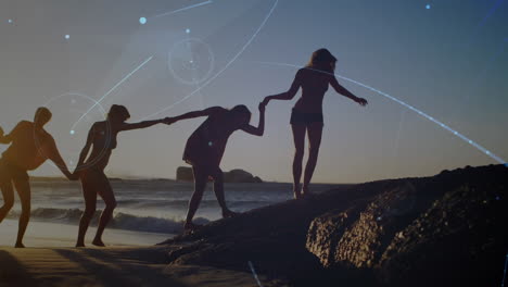 animation of glowing communication network over female friends holding hands walking on sunset beach