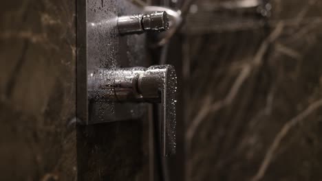 modern shower fixture with water droplets on marble wall