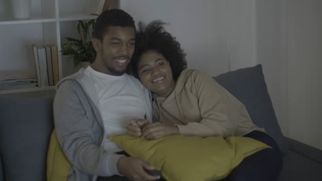 young couple having fun while watching tv in the dark