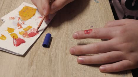 Applying-fake-blood-injury-on-index-finger-with-paintbush,-closeup