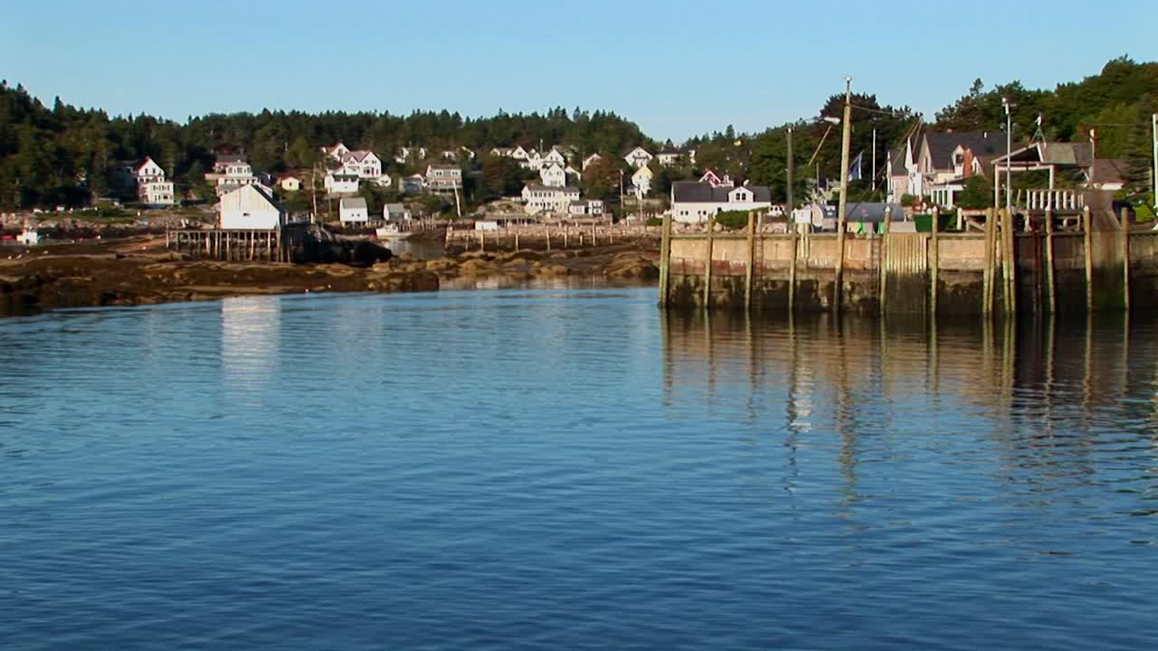 un barco pasa por un muelle y un pueblo de langostas en stonington, maine
