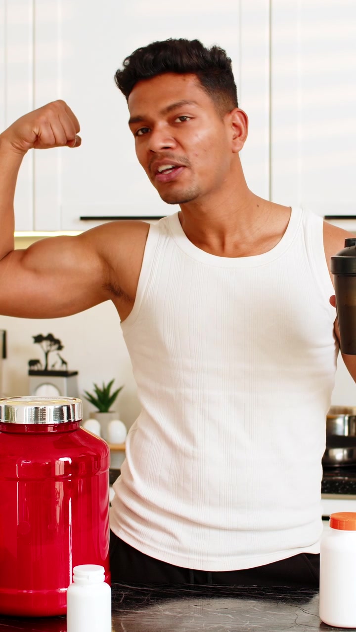 Indian man promoting sports nutrition and protein shake in kitchen for fitness diet and muscle gain