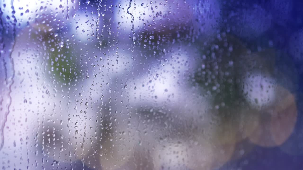 4k : Close-up of rain drops splashing against a window glass with light leaks.