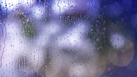 4k : close-up of rain drops splashing against a window glass with light leaks.