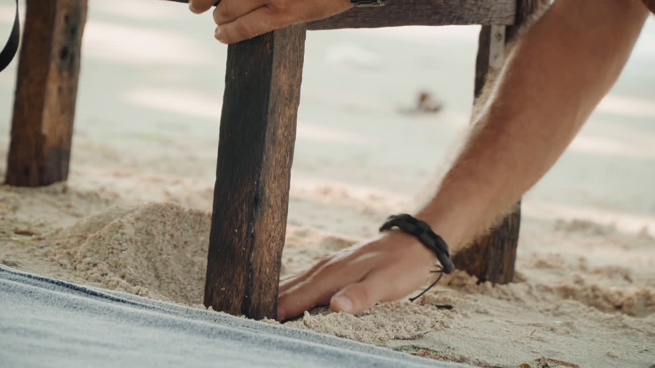 Man arrangerar noggrant te vid havet. Varsam person förbereder avkopplande te vid havet på ett träbord. Fridfull scen där mannen noggrant arrangerar teuppsättningen på ett träbord intill det lugna havet