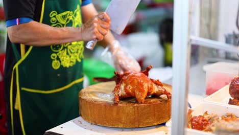 chef hábilmente corta pollo asado en el mercado
